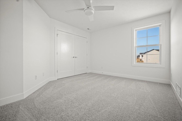 unfurnished bedroom with light colored carpet, ceiling fan, and a closet