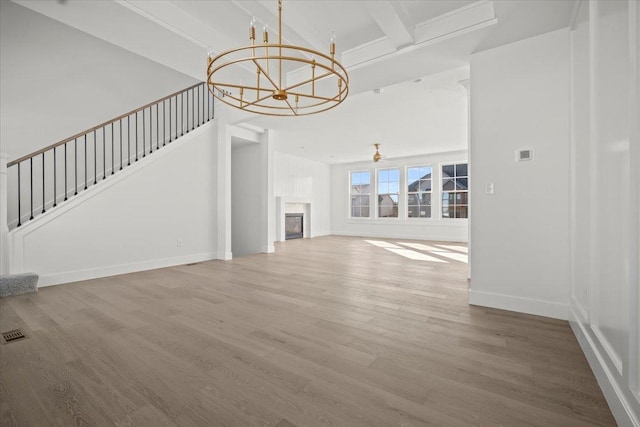 unfurnished living room with beam ceiling, hardwood / wood-style floors, and a chandelier