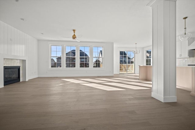 unfurnished living room with hardwood / wood-style flooring, a premium fireplace, and ceiling fan with notable chandelier