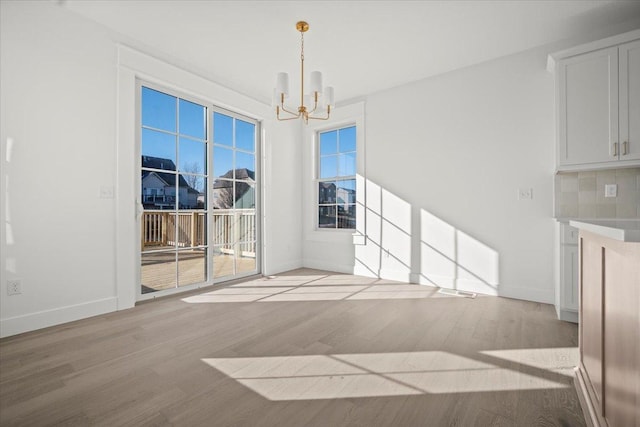 unfurnished dining area featuring a notable chandelier and light wood-type flooring