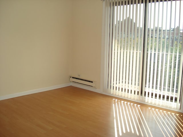 empty room with wood-type flooring and a baseboard heating unit