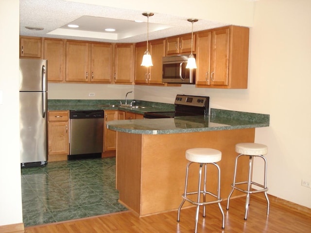 kitchen featuring decorative light fixtures, stainless steel appliances, sink, kitchen peninsula, and a breakfast bar