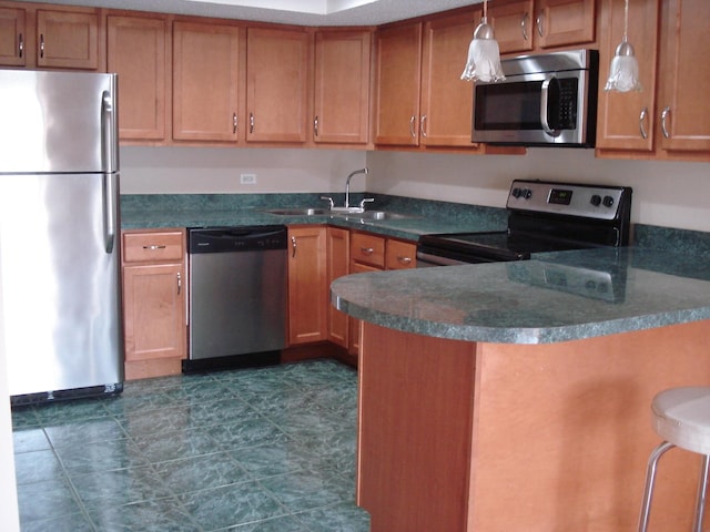 kitchen featuring hanging light fixtures, appliances with stainless steel finishes, kitchen peninsula, and a breakfast bar area