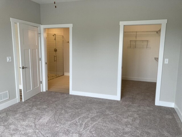 unfurnished bedroom with a closet, a spacious closet, and carpet floors