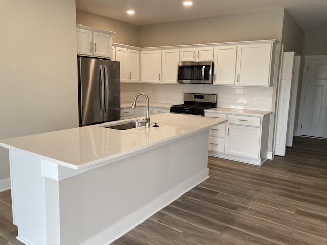 kitchen featuring white cabinets, appliances with stainless steel finishes, tasteful backsplash, sink, and a center island with sink