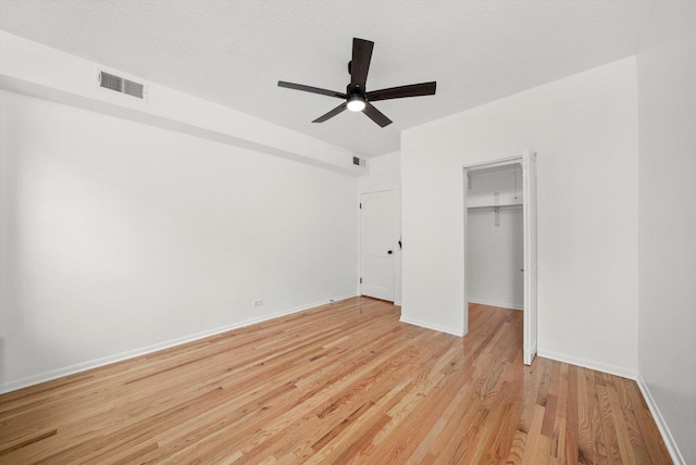 unfurnished bedroom featuring ceiling fan, a textured ceiling, a closet, and light hardwood / wood-style flooring