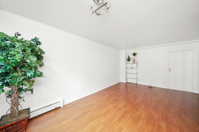 unfurnished living room with baseboard heating and hardwood / wood-style floors