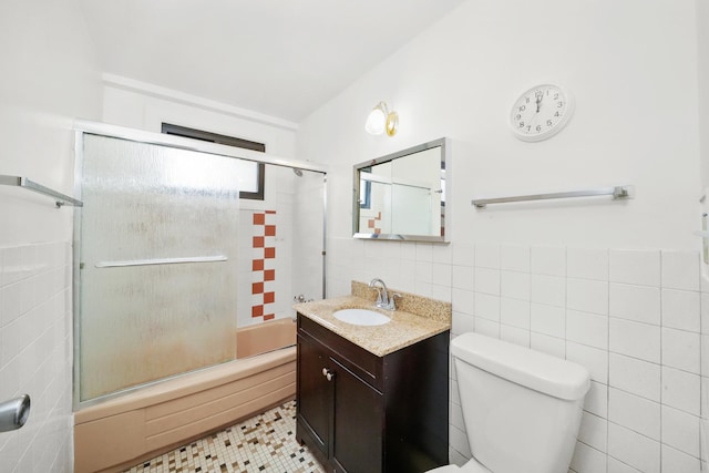 full bathroom featuring vanity, toilet, enclosed tub / shower combo, and tile walls