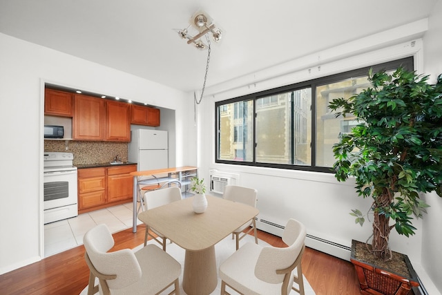 dining area with an AC wall unit, sink, and a baseboard radiator