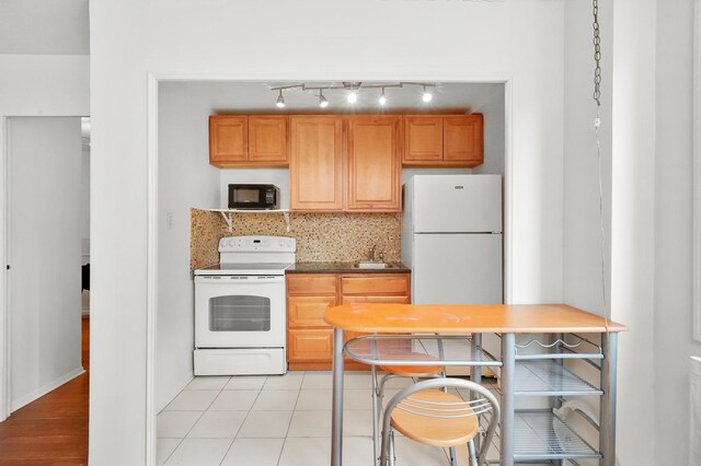 kitchen featuring sink, light tile patterned flooring, white appliances, and decorative backsplash