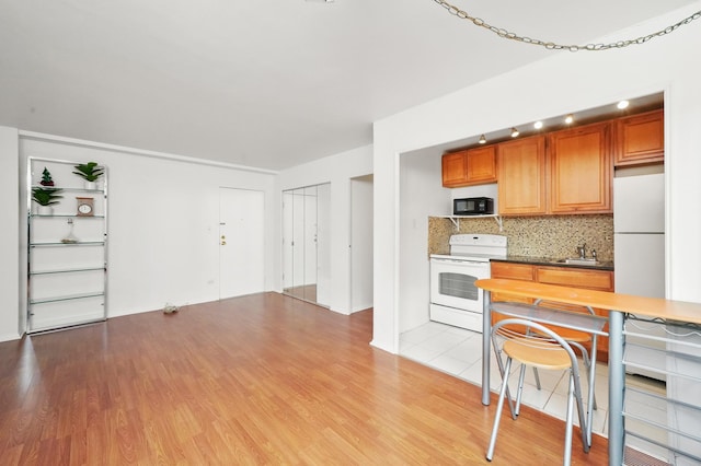 kitchen featuring sink, white appliances, tasteful backsplash, and light wood-type flooring