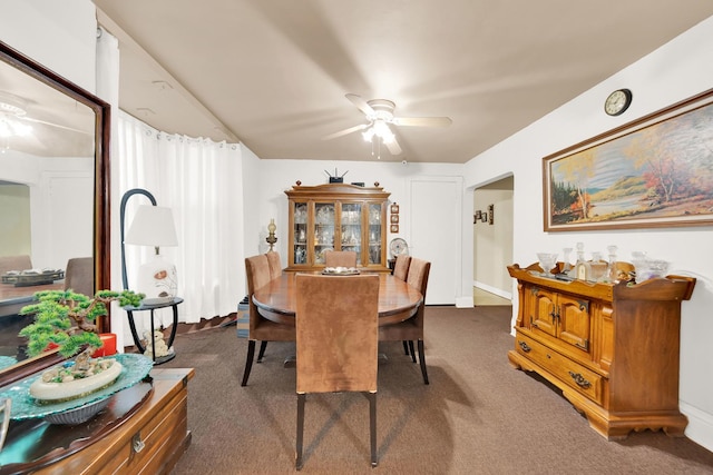 dining space with ceiling fan and dark colored carpet