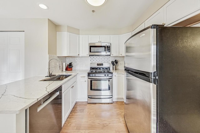 kitchen with sink, white cabinetry, light stone countertops, and appliances with stainless steel finishes