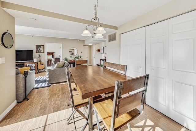 dining area featuring light hardwood / wood-style flooring and a notable chandelier