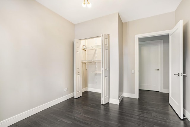 unfurnished bedroom featuring a closet, a spacious closet, and dark hardwood / wood-style flooring