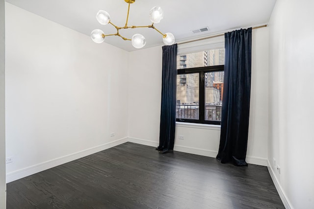 empty room with an inviting chandelier and dark hardwood / wood-style flooring