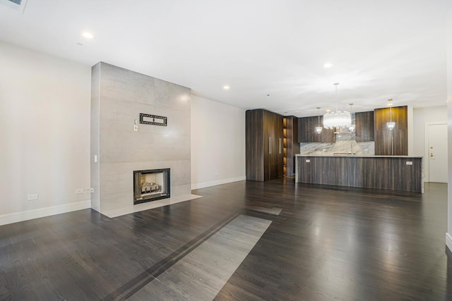 unfurnished living room featuring dark wood-type flooring and a fireplace