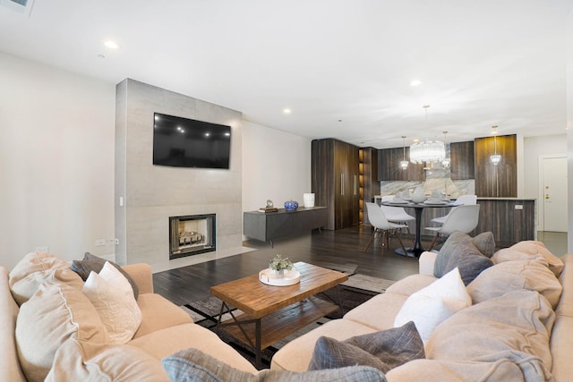 living room with a tiled fireplace and dark wood-type flooring