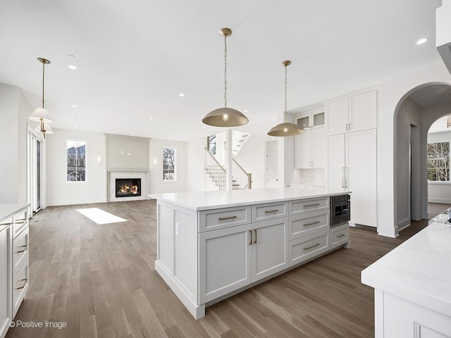 kitchen with white cabinetry, decorative light fixtures, dark hardwood / wood-style floors, and a kitchen island