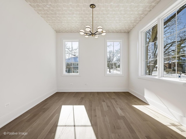 unfurnished dining area with brick ceiling, a chandelier, and dark hardwood / wood-style flooring