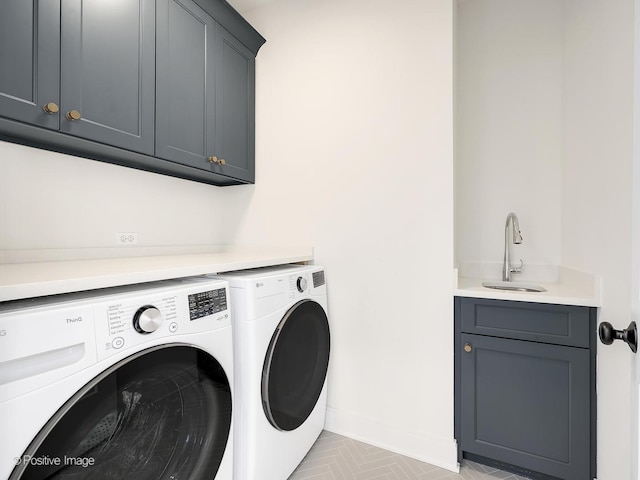 laundry area featuring sink, light tile patterned floors, cabinets, and washing machine and clothes dryer