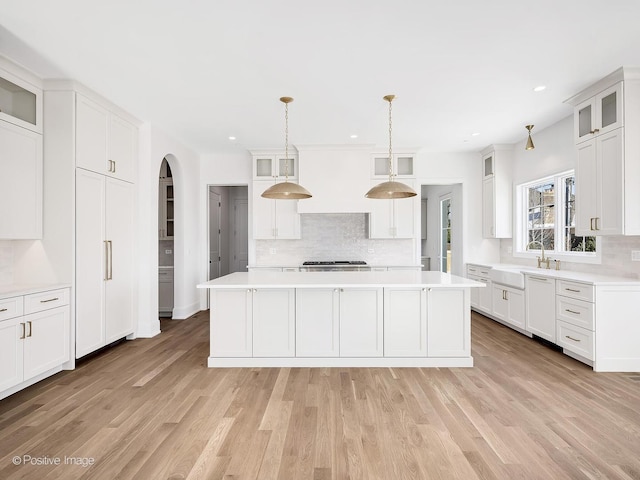 kitchen featuring white cabinetry, premium range hood, a center island, and hanging light fixtures