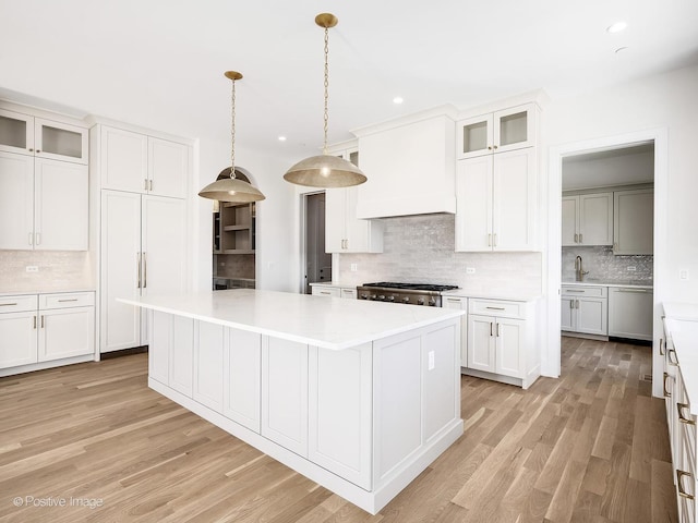 kitchen featuring sink, hanging light fixtures, tasteful backsplash, white cabinets, and a kitchen island