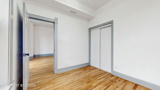 unfurnished bedroom featuring wood-type flooring and a closet