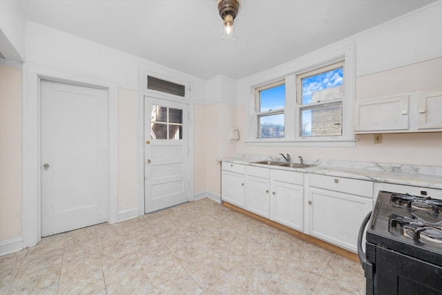 kitchen with sink, white cabinetry, gas stove, and light stone counters