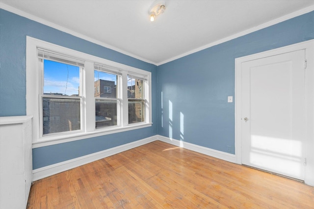 spare room featuring light wood-type flooring and ornamental molding