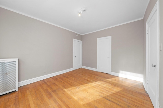 unfurnished bedroom featuring crown molding, radiator heating unit, wood-type flooring, and a closet