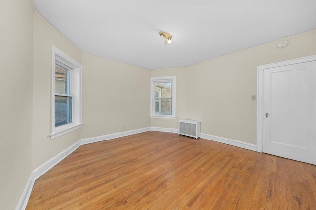 unfurnished room featuring light hardwood / wood-style floors, radiator, and plenty of natural light