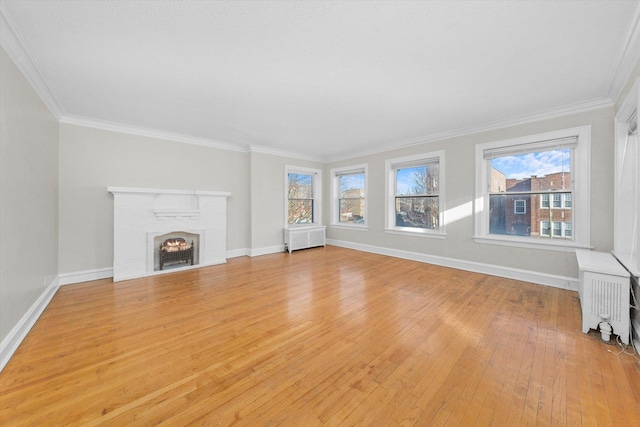 unfurnished living room featuring radiator, crown molding, and a healthy amount of sunlight