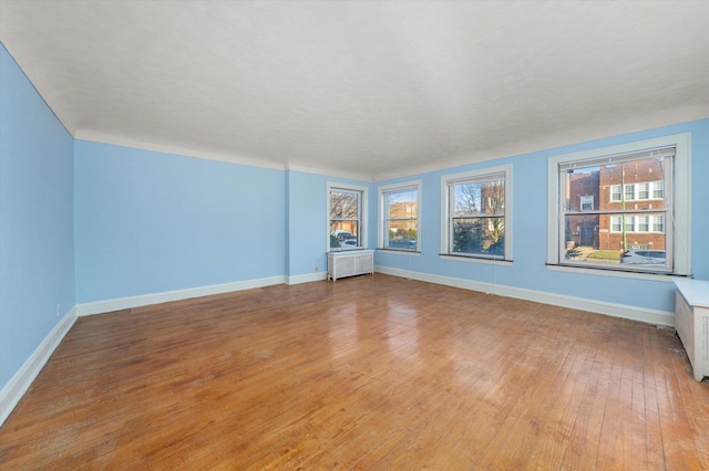 spare room with radiator heating unit and light hardwood / wood-style flooring