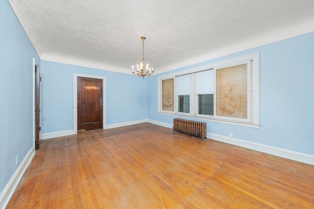 unfurnished room featuring light hardwood / wood-style flooring, radiator, an inviting chandelier, and a textured ceiling