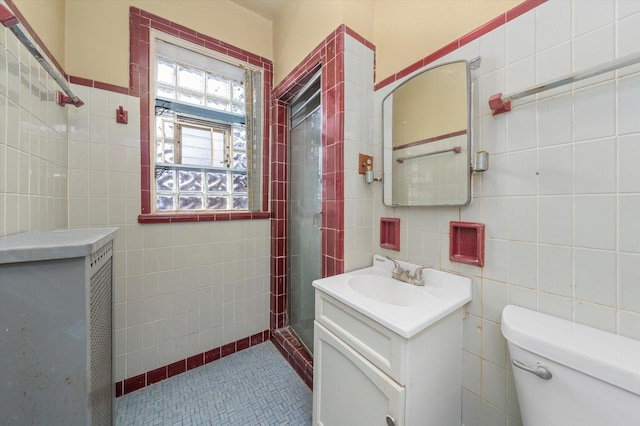 bathroom with toilet, vanity, tile patterned floors, and tile walls