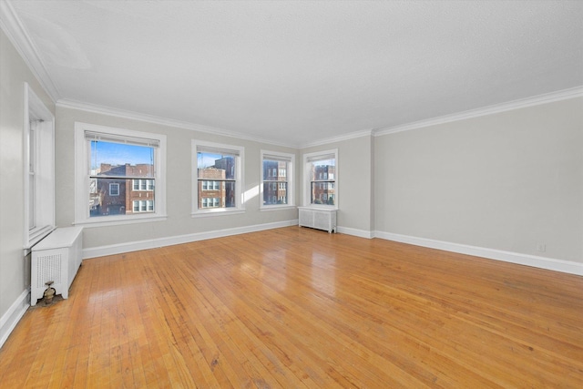 spare room featuring radiator heating unit, ornamental molding, light hardwood / wood-style floors, and a textured ceiling