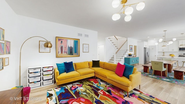 living room with light wood-type flooring and an inviting chandelier