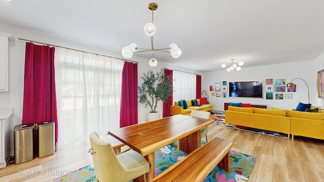 dining area featuring a healthy amount of sunlight, light hardwood / wood-style floors, and a notable chandelier