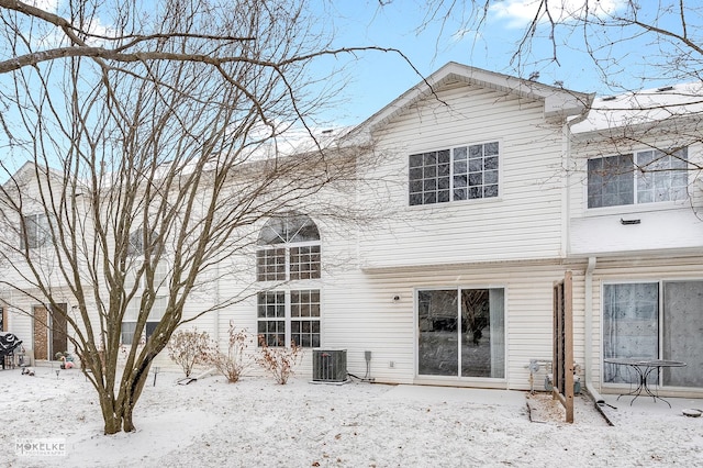 snow covered rear of property featuring central AC