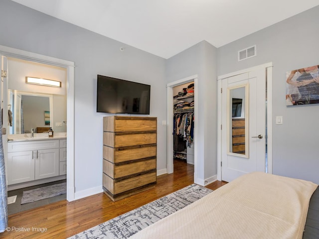 bedroom featuring connected bathroom, sink, a spacious closet, light hardwood / wood-style flooring, and a closet