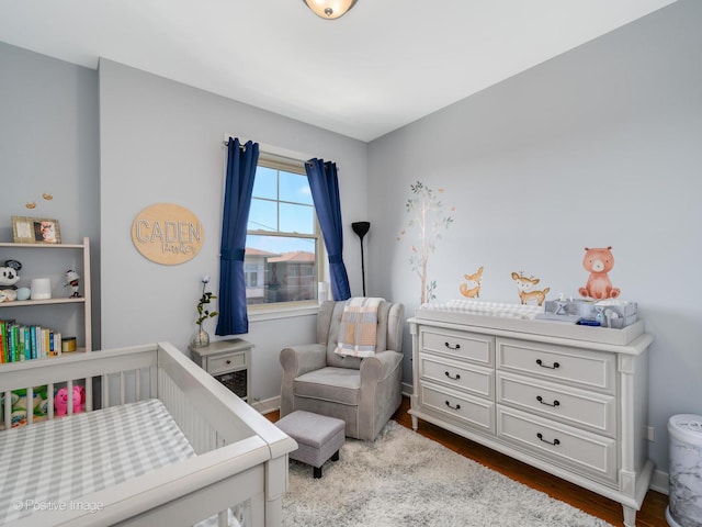 bedroom with hardwood / wood-style flooring and a nursery area