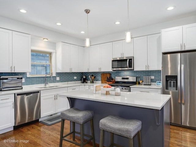 kitchen featuring white cabinetry, appliances with stainless steel finishes, sink, and pendant lighting