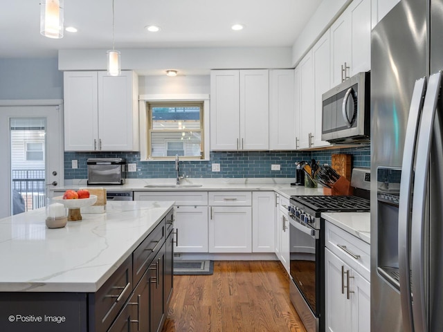 kitchen with stainless steel appliances, sink, pendant lighting, and white cabinets