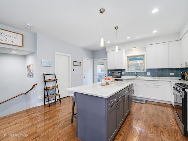 kitchen with white cabinetry, pendant lighting, and stainless steel gas range