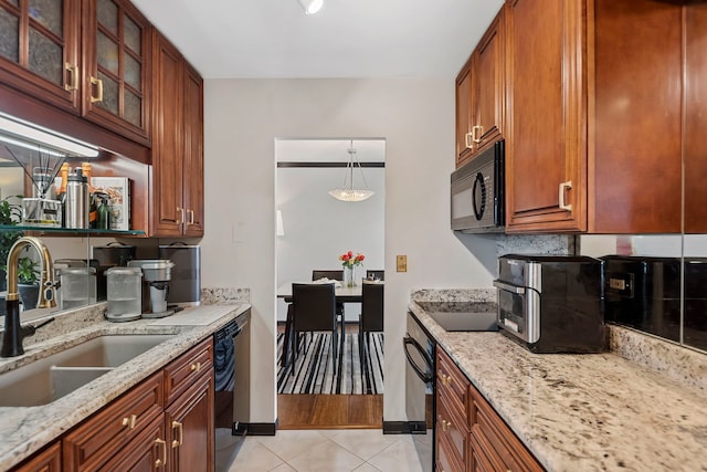 kitchen with sink, light tile patterned floors, light stone counters, and black appliances