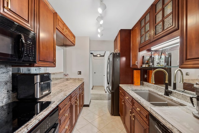 kitchen featuring light stone counters, light tile patterned floors, sink, and black appliances