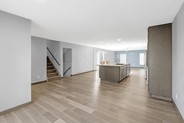 unfurnished living room with sink, light hardwood / wood-style flooring, and ceiling fan