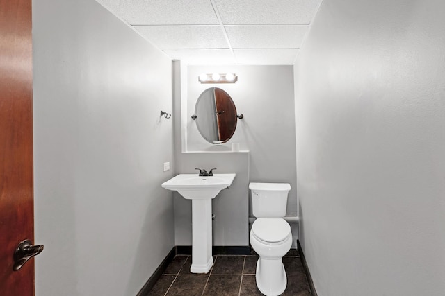 bathroom with tile patterned flooring, a drop ceiling, and toilet