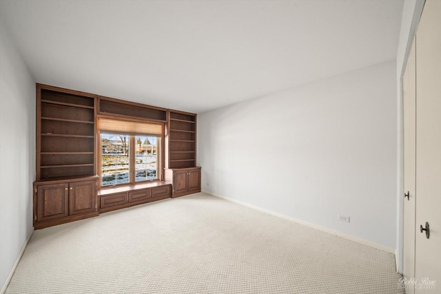 spare room featuring light colored carpet and built in shelves